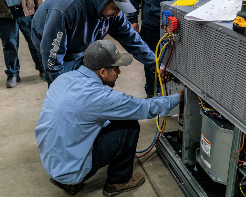 JC Melton employees repairing air conditioning unit