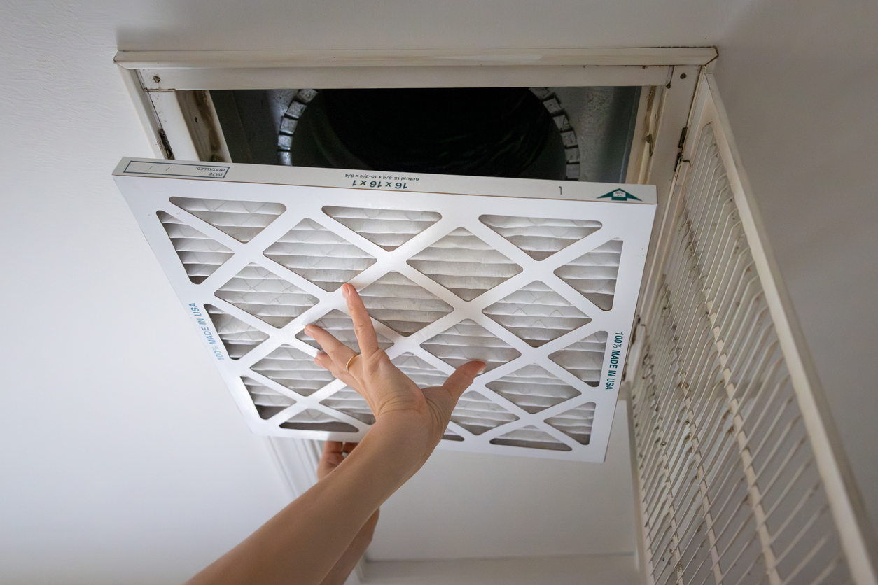 AC technician inspecting ductwork to fix uneven cooling in a Fresno home.