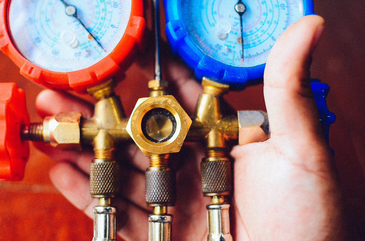 Technician checking AC refrigerant levels with a manifold gauge
