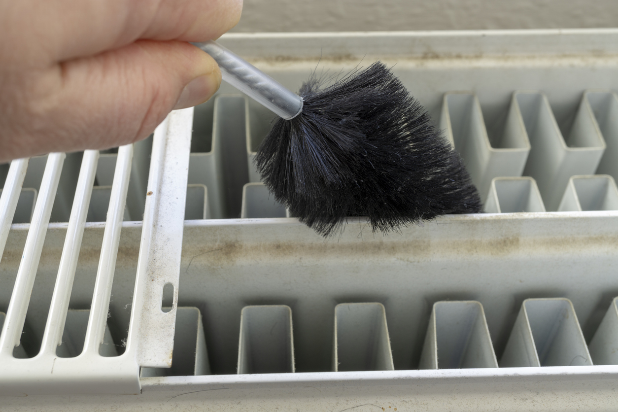 Technician cleaning AC condenser coils during a tune-up